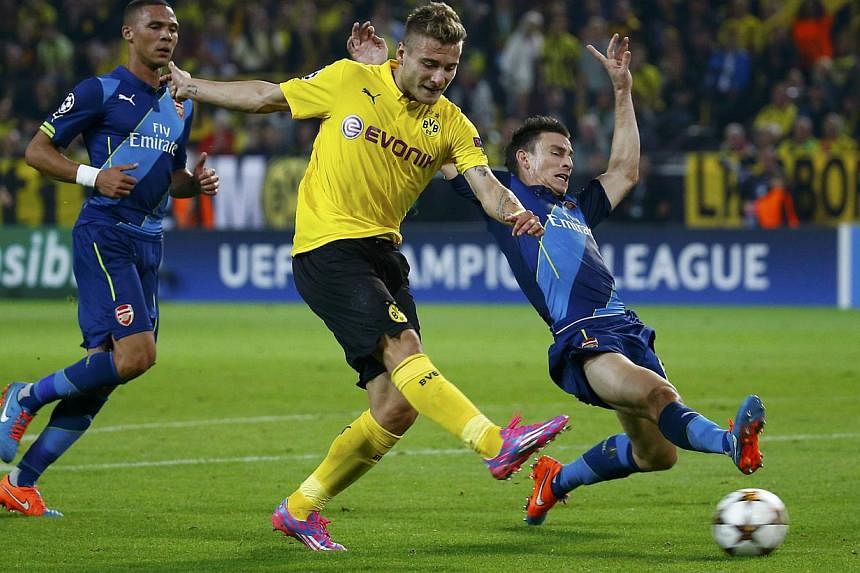 Borussia Dortmund's Ciro Immobile scores a goal past Arsenal's Laurent Koscielny (right) during their Champions League group D soccer match in Dortmund on Sept 16, 2014. -- PHOTO: REUTERS