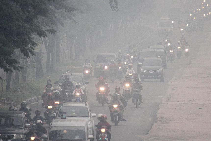 Thick haze blanketing a road in Pekanbaru in Riau yesterday. Environment Minister Balthasar Kambuaya told Parliament the move to ratify the pact would benefit Indonesia the most as it would better protect its citizens from the effects of forest fires