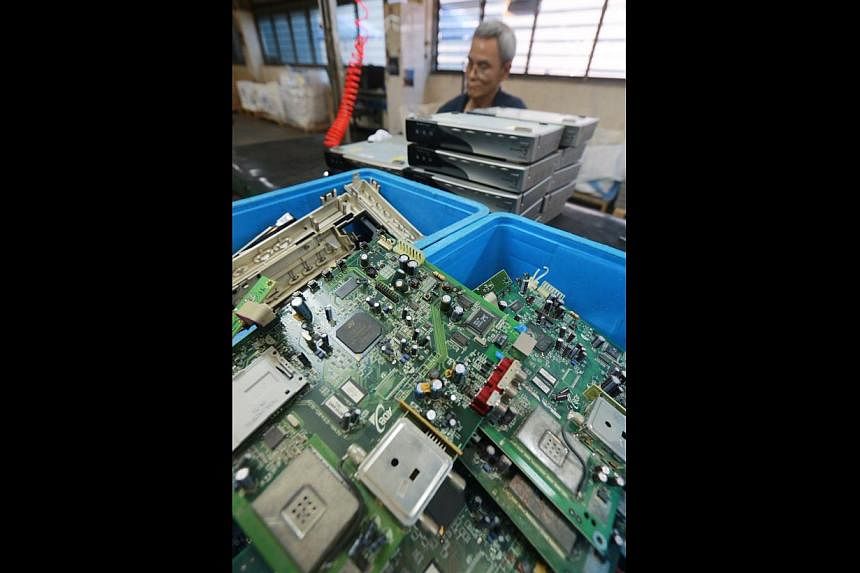 An employee dismantling electronics at home-grown electronic waste recycling firm TES-AMM’s recycling plant near Joo Koon. Over 5,600kg of electronic waste has been collected so far this year. -- PHOTO: LIANHE ZAOBAO