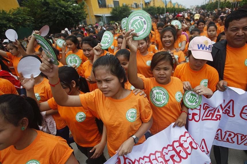 Garment workers hold stickers during a protest calling for higher wages in Phnom Penh on Sept 17, 2014. -- PHOTO: REUTERS