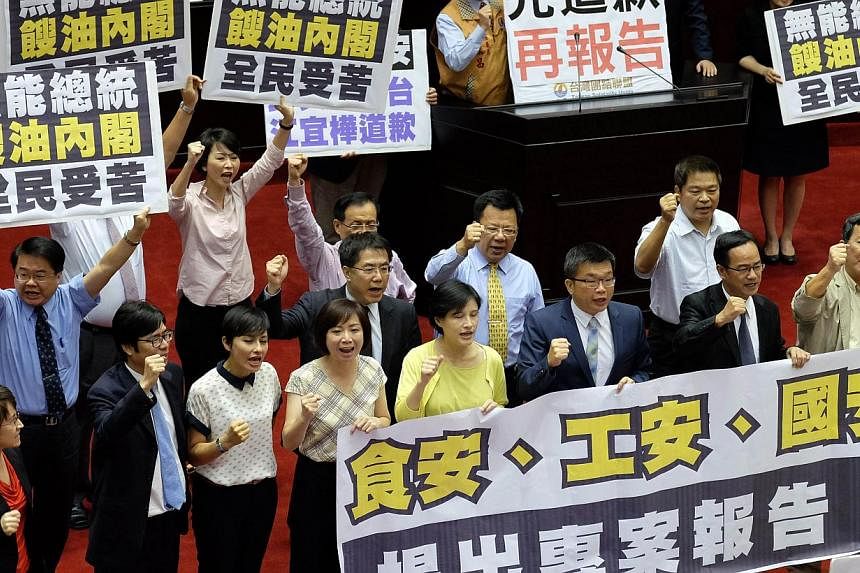 Opposition lawmakers from the Democratic Progressive Party (DPP) and Taiwan Solidarity Union (TSU) display placards demanding Premier Jiang Yih-hua (not in picture) to apologise for the gutter oil scandal before his speech on Sept 12, 2014.&nbsp;Taiw