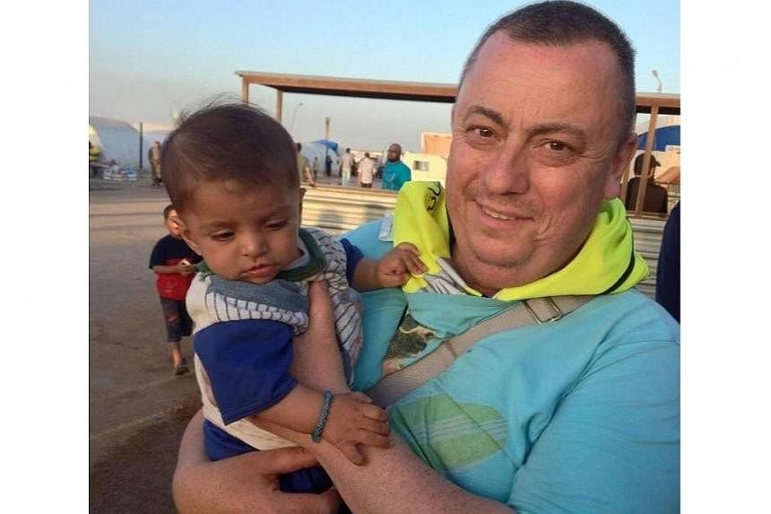 This handout image received from Britain's Foreign and Commonwealth Office on Sept 15, 2014 shows British aid worker, Alan Henning holding a child in a refugee camp on the Turkish-Syrian border. -- PHOTO: AFP