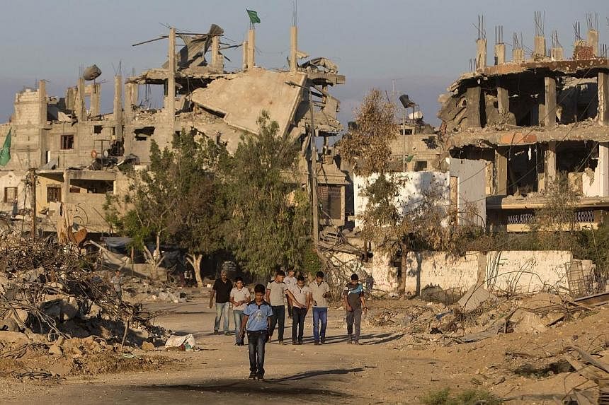 Palestinian boys walk past buildings which were destroyed by Israeli strikes on their way to school in the Shejaiya neighbourhood of Gaza City on Sept 14, 2014.&nbsp;Saudi Arabia has pledged US$500 million (S$625.15 million) to help rebuild Gaza, Pal