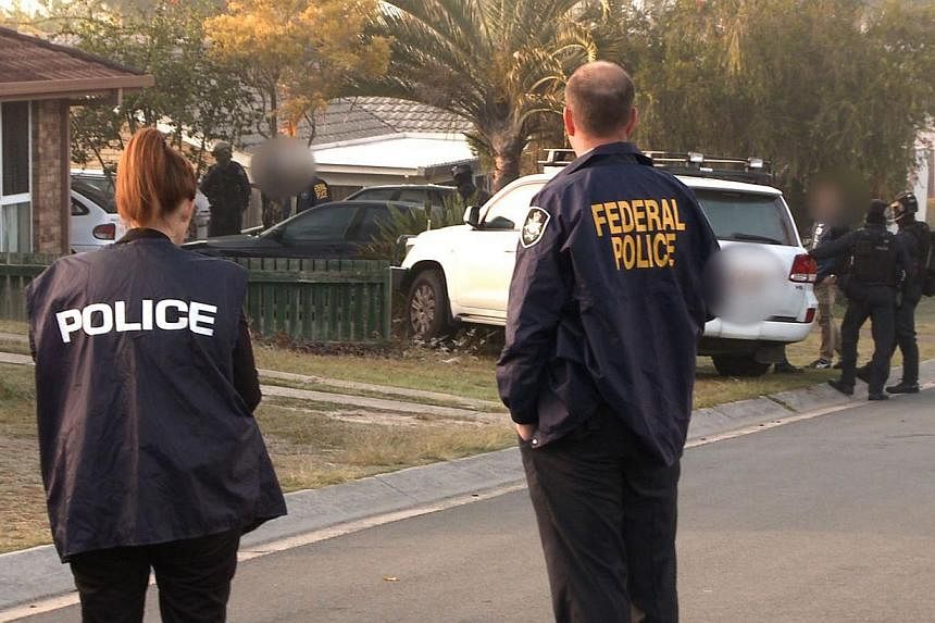 Australian Federal Police officers arresting two suspect after raiding an Islamic centre in Brisbane and seizing two men for alleged involvement in recruiting and sending jihadist fighters to Syria on Sept 10, 2014. -- PHOTO: AFP