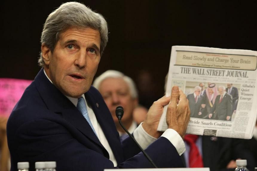 US Secretary of State John Kerry holds up a copy of the Wall Street Journal as he testifies during a hearing before the Senate Foreign Relations Committee on Sept 17, 2014 in Washington. -- PHOTO: AFP
