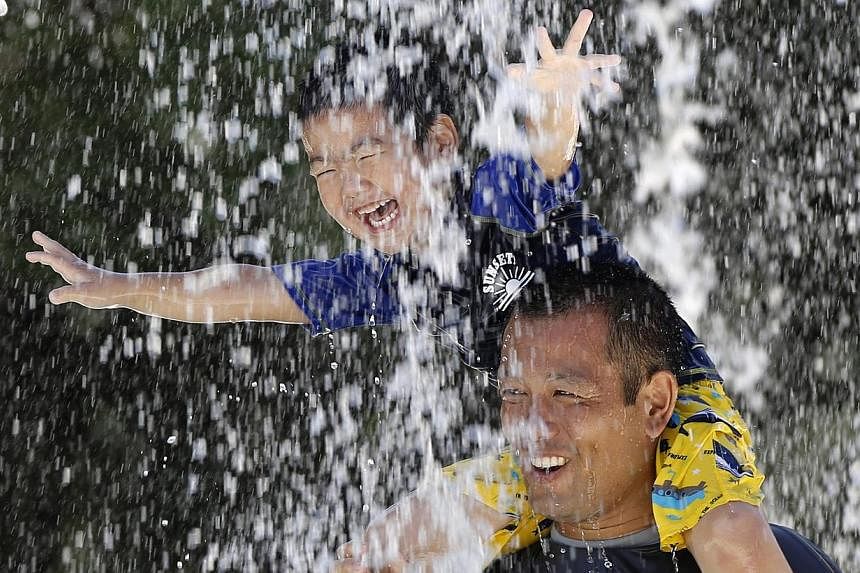 A boy sits on his father's shoulders as they cool down in the hot weather at a fountain in Tokyo on August 5, 2014. The temperature rose to 36 deg C in the Japanese capital. Last month was the hottest August on record for global average temperatures 