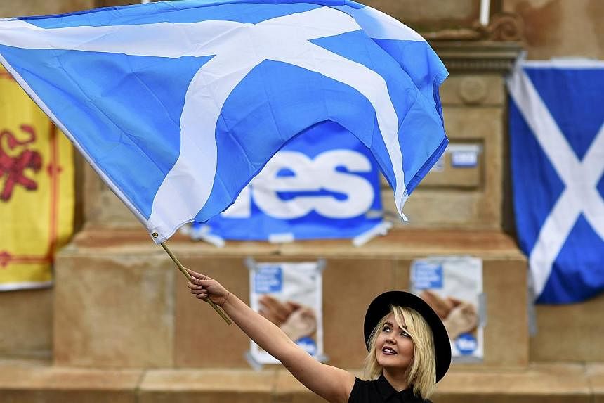 A woman waves a Scottish Saltire at a 'Yes' campaign rally in Glasgow, Scotland Sept 17, 2014. -- PHOTO: REUTERS