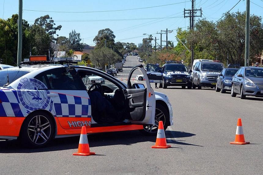 Police and other law enforcment agencies cordon off a street as forensic experts collect evidence inside a house in the Guildford area of Sydney on Sept 18, 2014. -- PHOTO: AFP