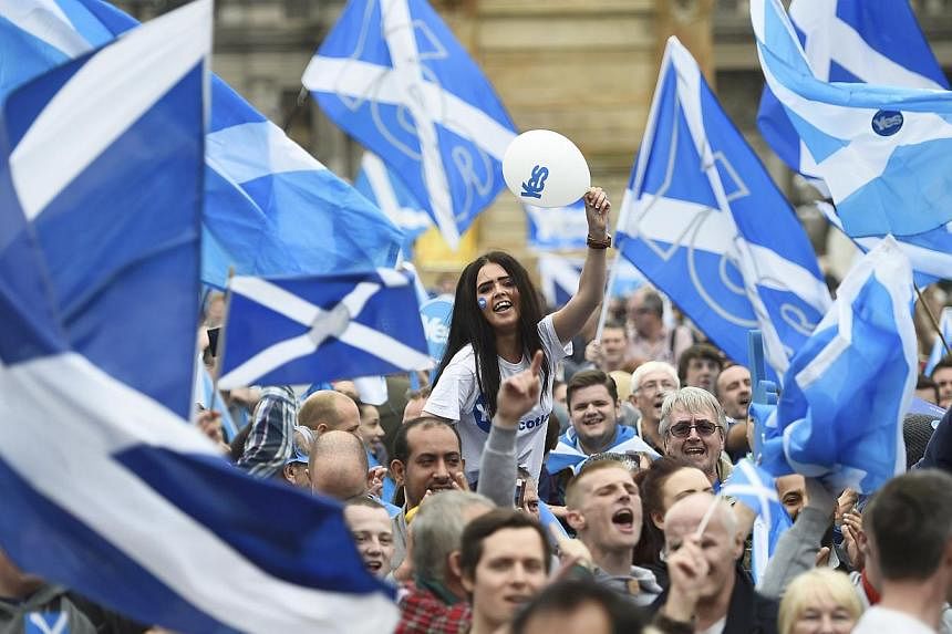 Campaigners wave Scottish Saltires at a 'Yes' campaign rally in Glasgow, Scotland on Sept 17, 2014. -- PHOTO: REUTERS