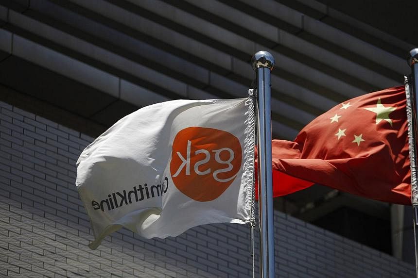A flag (left) bearing the logo of GlaxoSmithKline (GSK) flutters next to a Chinese national flag outside a GlaxoSmithKline office building in Shanghai in this July 12, 2013, file photo.&nbsp;A Chinese court on Friday fined British drugmaker GlaxoSmit