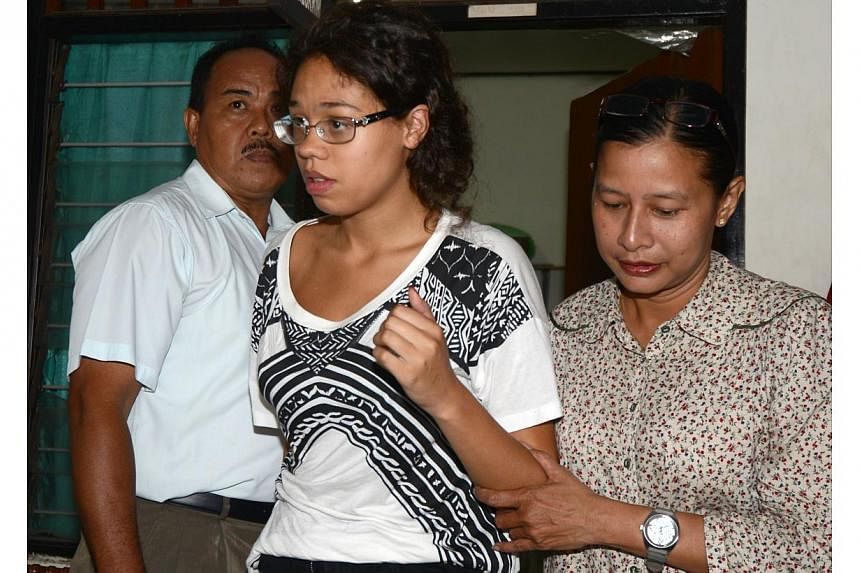 A police officer escorts suspect Lois Heather, 19, (centre) during an investigation at a police office in Nusa Dua on Indonesian resort island of Bali on Aug 13, 2014, after an American tourist's battered body was found in a suitcase at an exclusive 