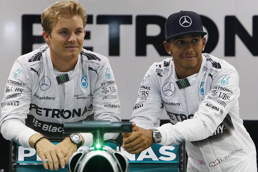 Mercedes Formula One drivers Nico Rosberg of Germany (left) and Lewis Hamilton of Britain pose for photos in their garage ahead of the Singapore F1 Grand Prix night race in Singapore on Sept 18, 2014. -- PHOTO: REUTERS