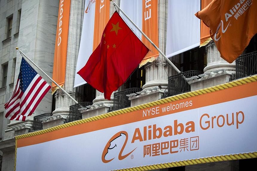 The Chinese (centre) and US (right) flags fly over signs of Alibaba Group Holding Ltd hung on the facade in front of the New York Stock Exchange before the company's initial public offering (IPO) under the ticker "BABA" in New York on Sept 19, 2014. 