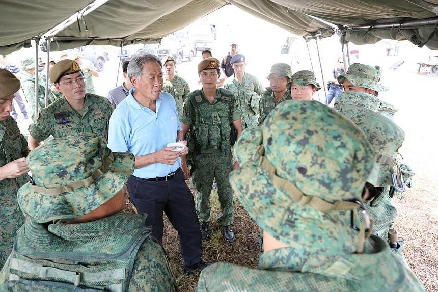 Minister for Defence Dr Ng Eng Hen (in blue) speaking with men from the 7th Singapore Infantry Brigade of HQ Guards. -- ST PHOTO:&nbsp;ONG WEE JIN