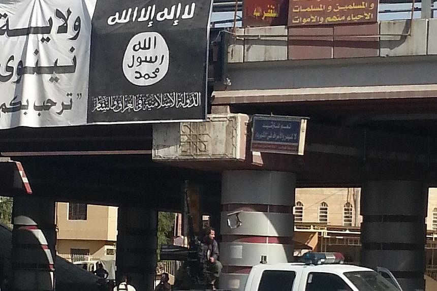 A fighter from the Islamic State, formerly known as the Islamic State of Iraq and the Levant (ISIL), mans an anti-aircraft gun mounted on the rear of a vehicle in Mosul July 16, 2014. The banner on the bridge reads: "Welcome to the State of Nineveh; 