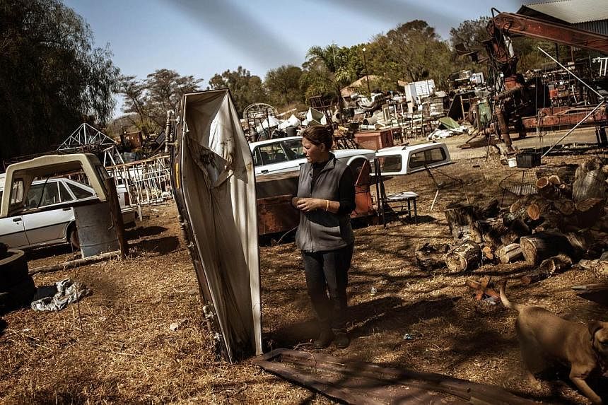 Scrapyard manager Rita Gathino stands by a displayed coffin close to their entrance gate on Aug 27, 2014 in Cullinan, South Africa. -- PHOTO: AFP