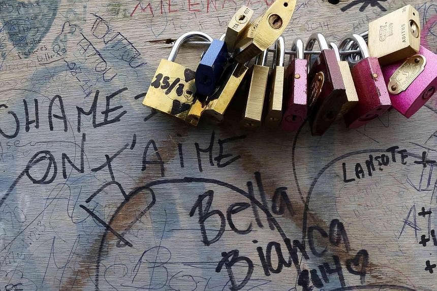 A panel with love locks and personal messages is seen of the Pont de l'Archeveche bridge, near the Notre Dame Cathedral, which is covered with thousands of padlocks in Paris on Aug 13, 2014. -- PHOTO: REUTERS