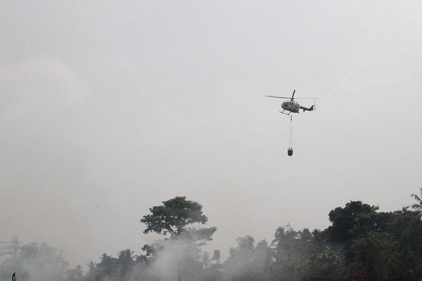 A helicopter operated by Indonesia's disaster mitigation agency conducting water bombing in Ogan Ilir, South Sumatra, yesterday.