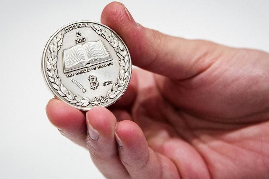 A file photo of a man holding a silver coin etched with cryptographic information for digital bitcoins.&nbsp;A US federal judge in Texas ordered Bitcoin Savings and Trust and its owner to pay a combined US$40.7 million (S$51.5 million) after the SEC 