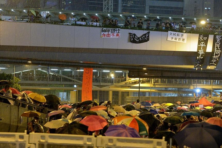 Umbrellas deployed during a sudden downpour as protesters block the road to the central business district in Hong Kong on Sept 30, 2014. -- ST PHOTO:&nbsp;KUA CHEE SIONG
