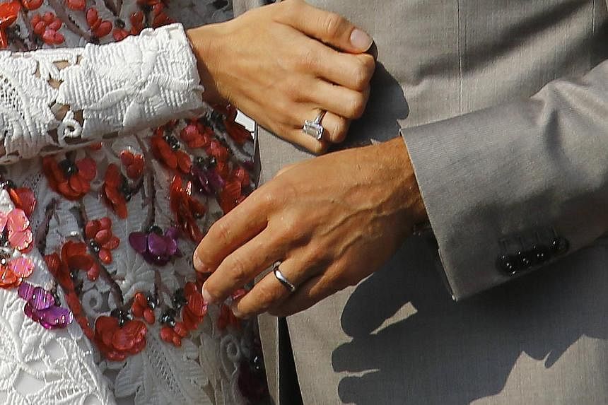 Wedding rings are seen on the hands of U.S. actor George Clooney (right) and his wife Amal Alamuddin as they stand in a water taxi on the Grand Canal in Venice on Sept 28, 2014. -- PHOTO: REUTERS