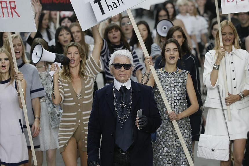 German designer Karl Lagerfeld appears with models who stage a demonstration at the end of his Spring/Summer 2015 women's ready-to-wear collection for French fashion house Chanel during Paris Fashion Week on Sept 30, 2014. -- PHOTO: REUTERS