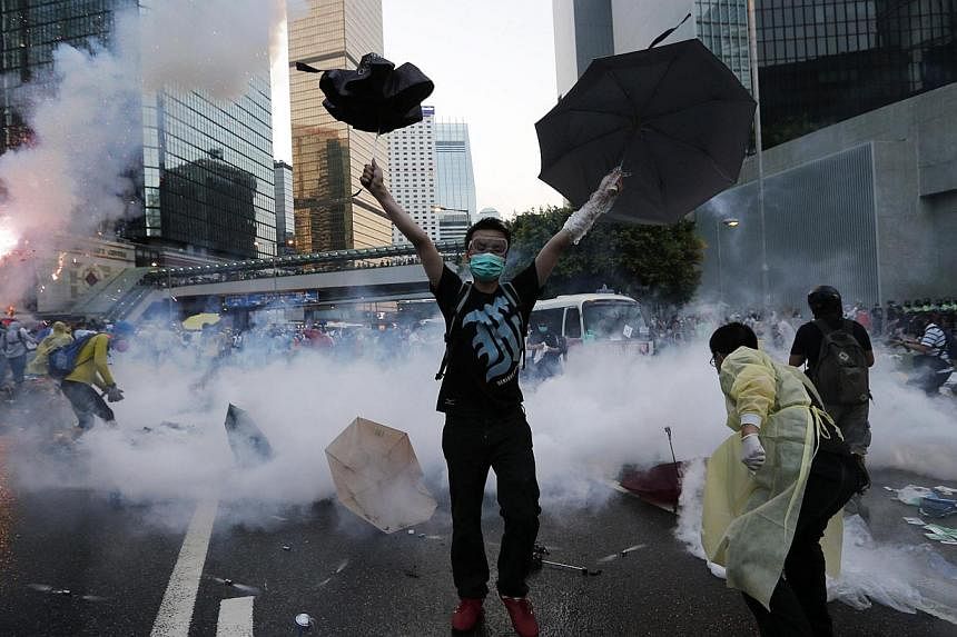 A protester raises his umbrellas in front of tear gas which was fired by riot police to disperse protesters blocking the main street to the financial Central district outside the government headquarters in Hong Kong, Sept&nbsp;28, 2014. -- PHOTO: REU