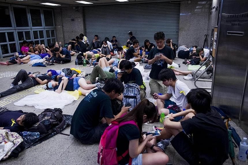 Pro-democracy demonstrators rest in an office building after overnight protests in the Wanchai district of Hong Kong on Oct 1, 2014. &nbsp;-- PHOTO: AFP