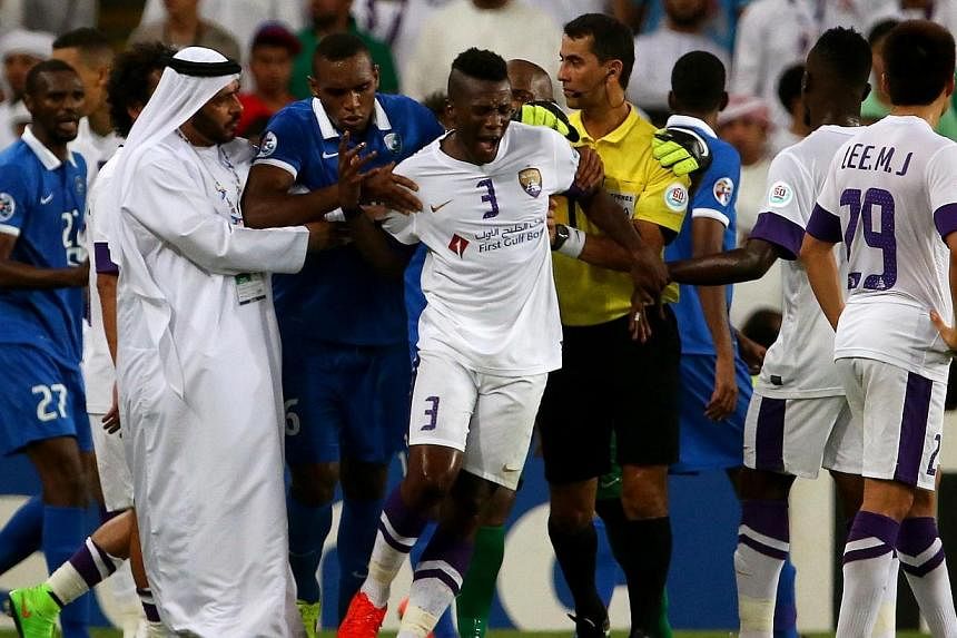 Players, officials and staff try to calm UAE's al-Ain forward Asamoah Gyan (centre, #3) following altercation between Al-Ain and Al-Hilal players during their AFC Champions League semi-final football match on Sept 30, 2014 at Hazza Bin Zayed Stadium 