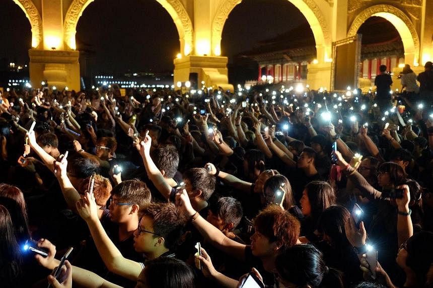 Students from Taiwan and Hong Kong raise their mobile phones in front of the Freedom square during a gathering in support of Hong Kong's pro-democracy protestors, in Taipei on Oct 1, 2014. -- PHOTO: AFP