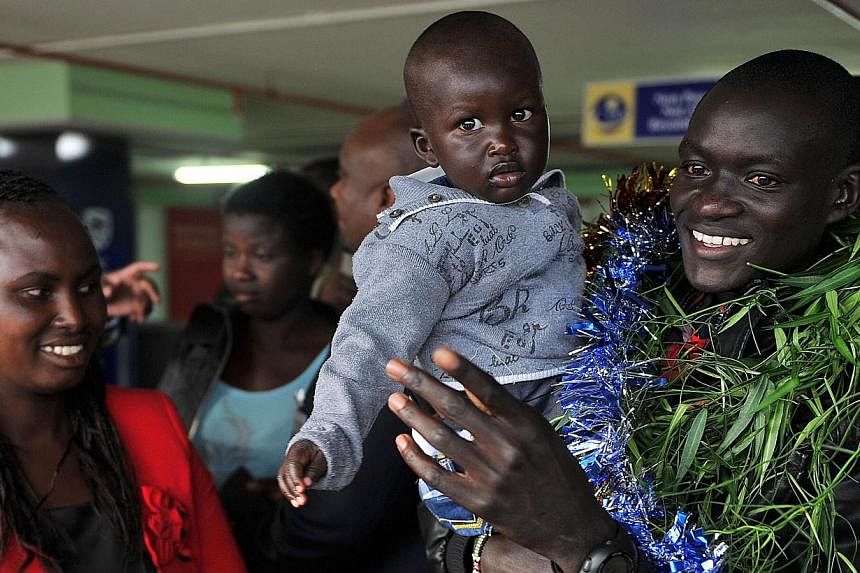 Kenya's Dennis Kimetto (right) holds his son Alvin after arriving in Nairobi on October 1, 2014, returning from Berlin where he clocked a world record of 2hr 02min 57sec to win the Berlin Marathon on Sept 28.&nbsp;Marathon world record breaker Dennis