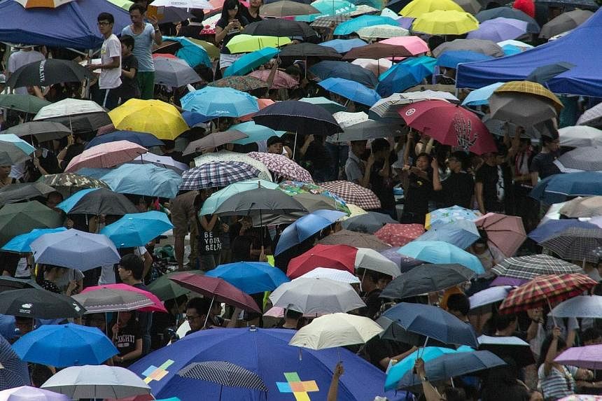 Pro-democracy protesters raise their umbrellas on cue as part of the demonstrations currently blocking central Hong Kong that have been dubbed the "umbrella revolution", on Oct 1, 2014. -- PHOTO: AFP