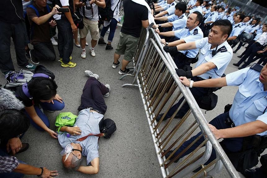Police officers try to remove a protester from the entrance to Hong Kong's Chief Executive Leung Chun Ying offices next to the government headquarters building in Hong Kong on Oct 2, 2014. -- PHOTO: REUTERS&nbsp;