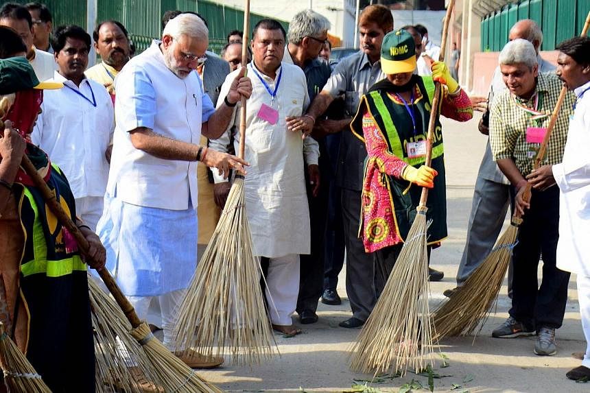 Indian Prime Minister Narendra Modi (left) sweeps a street in a residential colony in New Delhi on Oct 2, 2014. Mr Modi launched the Swachh Bharat Abhiyan, or Clean India Mission, to modernise sanitation within five years on Thursday, Oct 2, 2014, a 