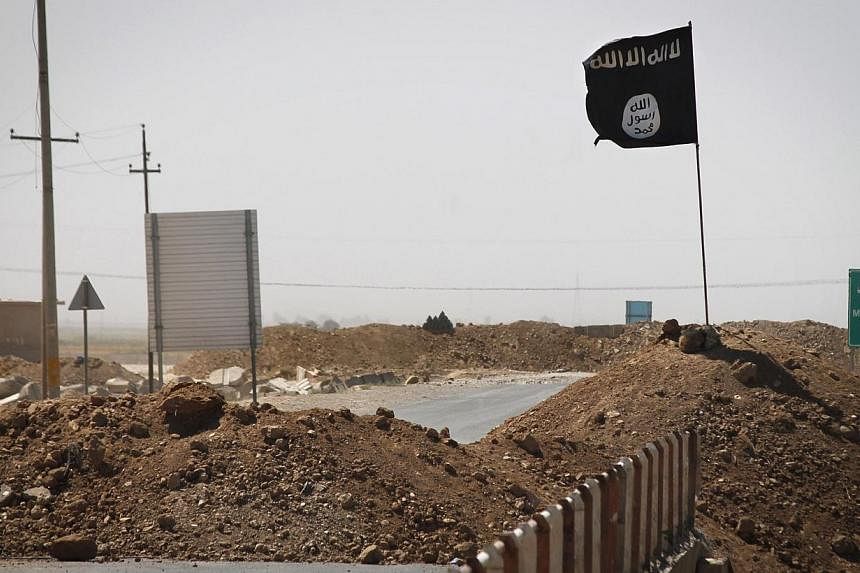 A file picture taken on Sept 11, 2014, shows a flag of the Islamic State group on the other side of a bridge on the road between Kirkuk and Tikrit. -- PHOTO: AFP