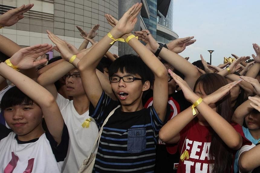 Scholarism founder Joshua Wong (centre) and other members chant slogans during a flag raising ceremony in Hong Kong on Oct 1, 2014. -- PHOTO: REUTERS