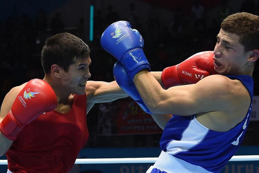 Kazakhstan's Daniyar Yeleussinov (left) lands a left on Uzbekistan's Israil Madrimov (right) in the men's welterweight (69kg) final boxing match during the 17th Asian Games at the Seonhak Gymnasium in Incheon on Oct 3, 2014. -- PHOTO: AFP