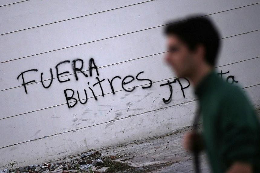 A man passes by grafitti that reads "Vultures, get out" in Buenos Aires on Sept 24, 2014. Argentine President Cristina Fernandez characterises hedge funds suing the country for full repayment of defaulted debt as "vultures" out to wreck Argentina's f
