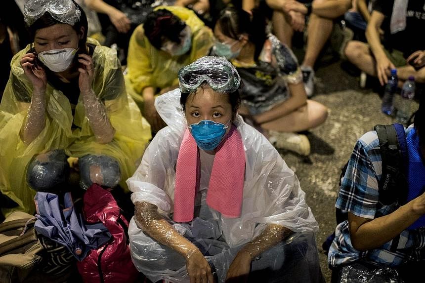 A woman wearing protective gear in anticipation of police action sits outside the central government complex on a blockaded road in Hong Kong on Oct 2, 2014. -- PHOTO: AFP