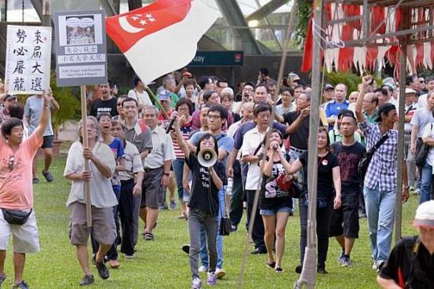 Activists Han Hui Hui (with loudspeaker) and Roy Ngerng (carrying state flag) with supporters at the Return Our CPF rally, marching round Hong Lim Park on Sept 27, 2014. -- ST PHOTO: LIM SIN THAI