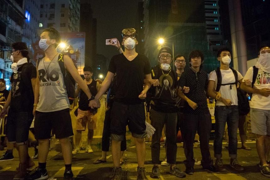 Pro-democracy demonstrators link arms and guard their protest camp in Mongkok on Oct 5, 2014. -- PHOTO: AFP&nbsp;