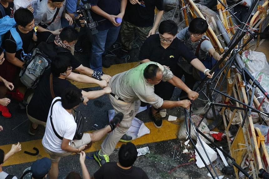 A man is pulled back and kicked as he tries to remove a barricade set up by pro-democracy protesters blocking a main road at Hong Kong's shopping Mongkok district on Oct 4, 2014. -- PHOTO: REUTERS&nbsp;