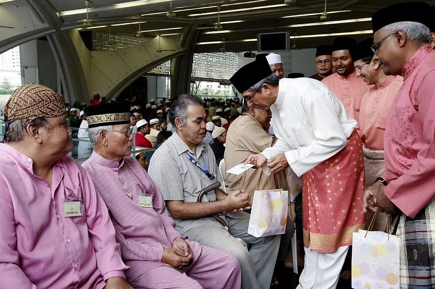 Minister-in-charge of Muslim Affairs Yaacob Ibrahim (in white), together with Muis president Mohd Alami Musa (second from right) and chairman of Assyafaah Mosque Mohd Salleh K Moideen (right) distributing meat to (from left) Mr Mohd Isa, Mr Jamaludin