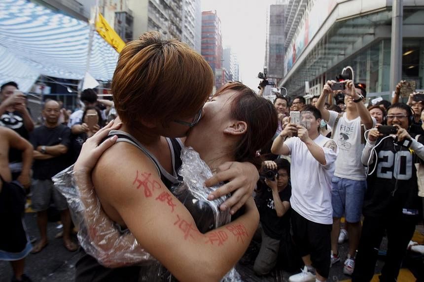 Yau Chi-hang, 22, a university student and pro-democracy protester, kisses fellow protester Crystal Chan, 21, after she agreed to his marriage proposal, at Mongkok shopping district in Hong Kong on Oct 5, 2014, to the cheers of the crowd. -- PHOTO: R