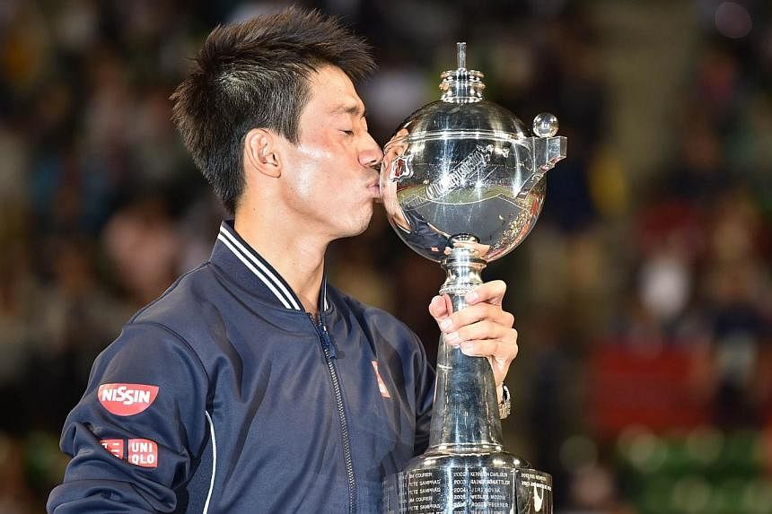 Kei Nishikori of Japan kisses the trophy during the awards ceremony after the men's singles final against Milos Raonic of Canada at the Japan Open tennis tournament in Tokyo on Oct 5, 2014.&nbsp;Local hero Nishikori beat Raonic 7-6 (7-5), 4-6, 6-4. -