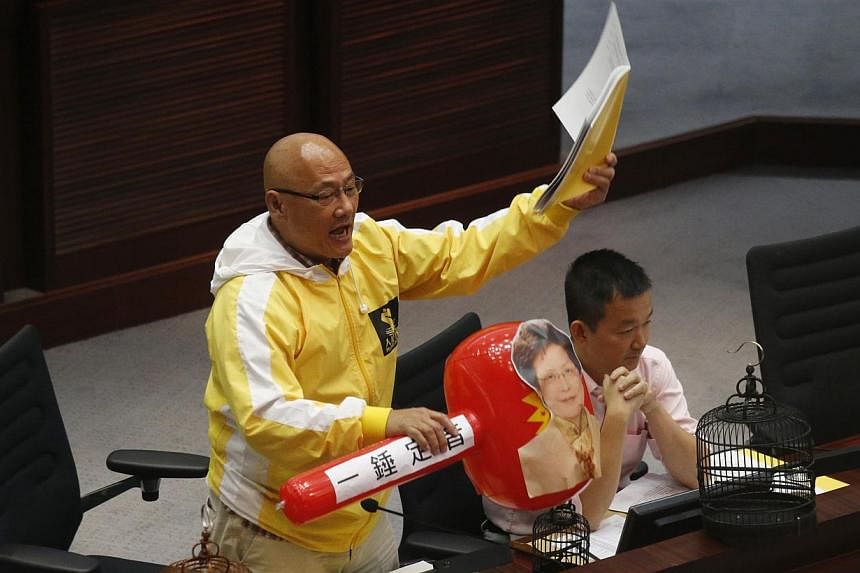 Pro-democracy lawmaker Albert Chan shouts while holding an electoral reforms consultation report and a plastic hammer featuring a portrait of Hong Kong Chief Secretary Carrie Lam, during a meeting with Lam on proposing electoral reforms at the Legisl
