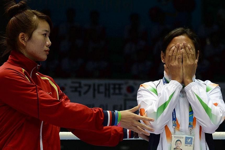 This file photo taken on Oct 1, 2014, shows bronze medallist Luu Thi Duyen (left) of Vietnam urging India's Laishram Sarita Devi to go on to the podium after she decided to refuse to accept her bronze medal during the women's lightweight (57-60kg) bo