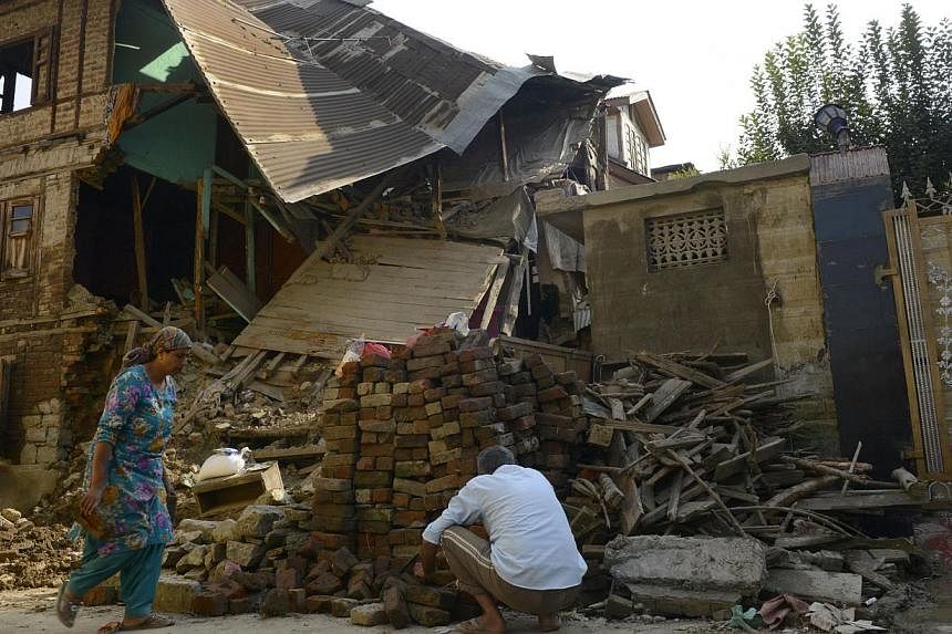 A Kashmiri man works at his flood-damaged house in Srinagar on Oct 3, 2014.&nbsp;Pakistan on Saturday barred activists from taking relief goods intended for flood victims to the border of Indian-controlled Kashmir, where delays in aid have created wi