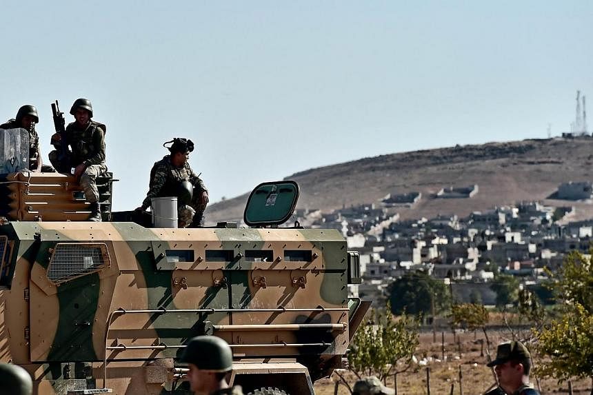 Turkish soldiers stand in front of the Syrian town of Ain al-Arab, known as Kobane by the Kurds, at the Mursitpinar border crossing on the Turkish-Syrian border in the southeastern town of Suruc, Sanliurfa province, on Oct 5, 2014. -- PHOTO: AFP