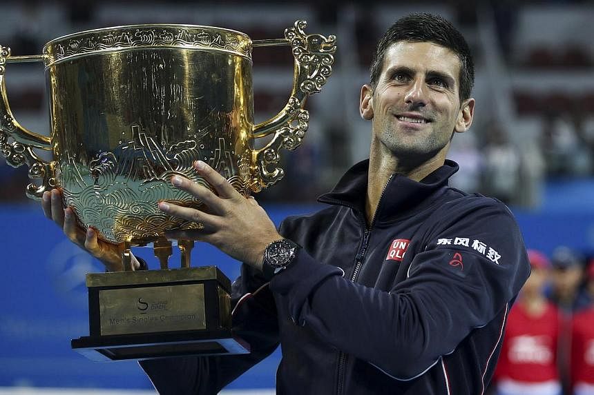 Novak Djokovic of Serbia holds his trophy as he poses for pictures after winning the men's singles final match against Tomas Berdych of the Czech Republic at the China Open tennis tournament in Beijing on Oct 5, 2014. -- PHOTO: REUTERS